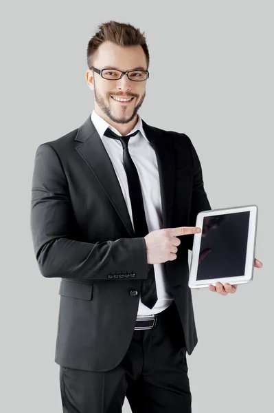 Man in formalwear and glasses holding a digital tablet and pointing it