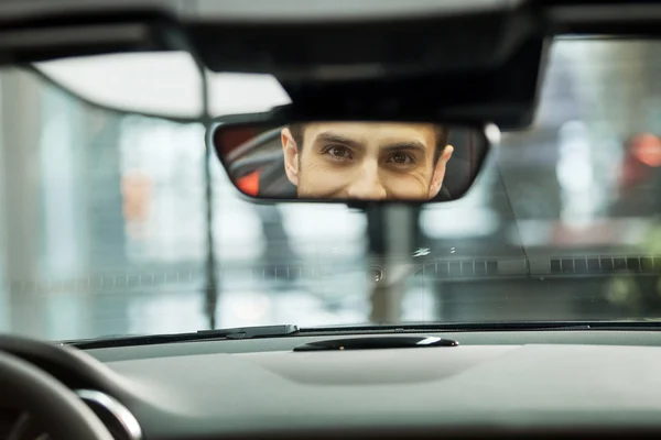 Men sitting at front seat of the car looking at review mirror