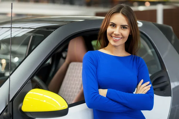 Woman standing near her new car at the dealership