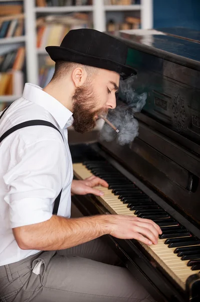 Profile of bearded men playing piano and smoking cigarette