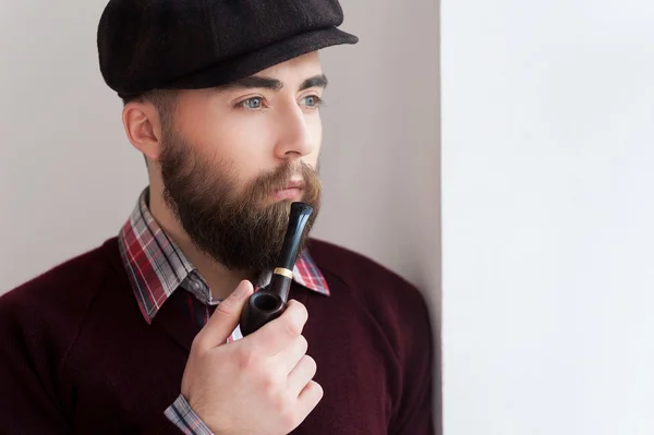 Man in hat smoking a pipe and looking away