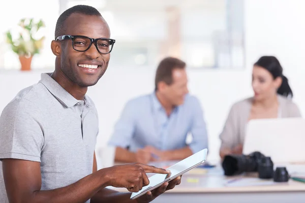 African man working on digital tablet and smiling