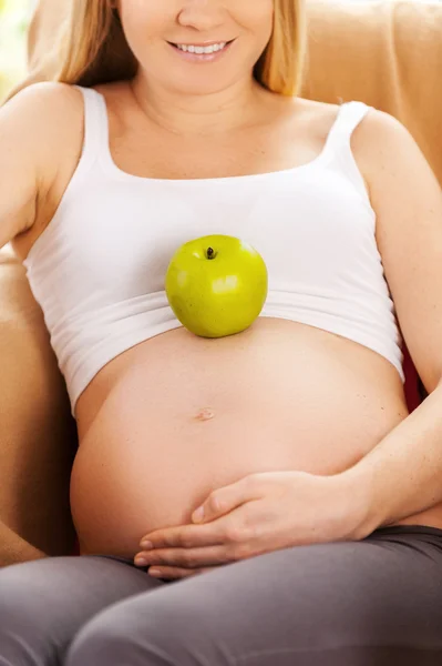 Pregnant woman, apple laying on her belly