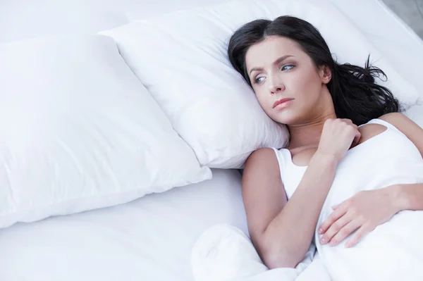 Woman lying on the bed and looking on empty pillow