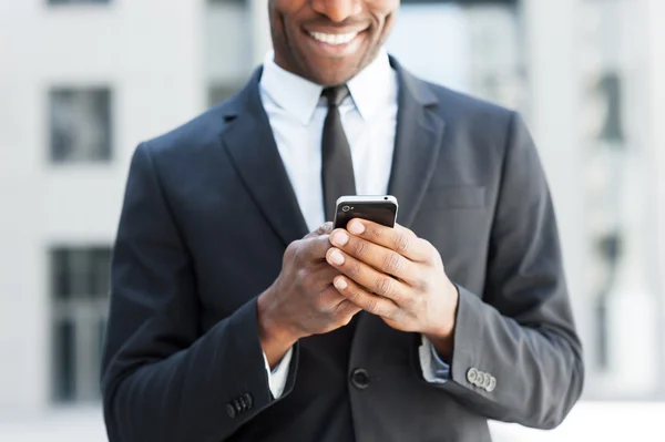 African man in formal wear holding mobile phone