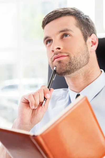 Man in shirt and tie holding note pad