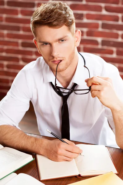 Man in shirt and tie writing in note pad