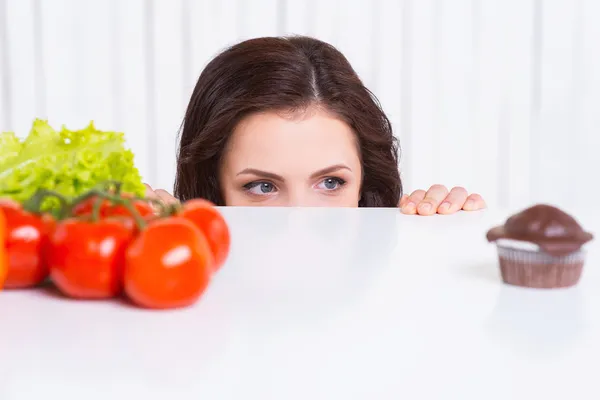 Woman choosing vegetables or muffin