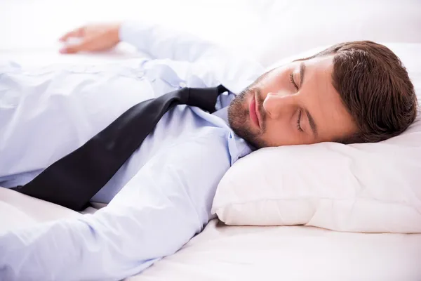 Man in shirt and tie sleeping in bed