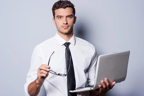 Man in shirt and tie holding laptop