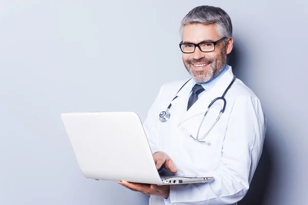 Cheerful doctor with laptop.
