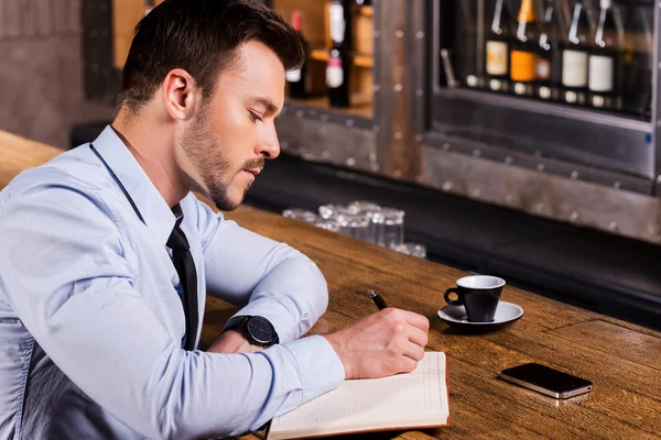 Man in shirt and tie writing in note pad
