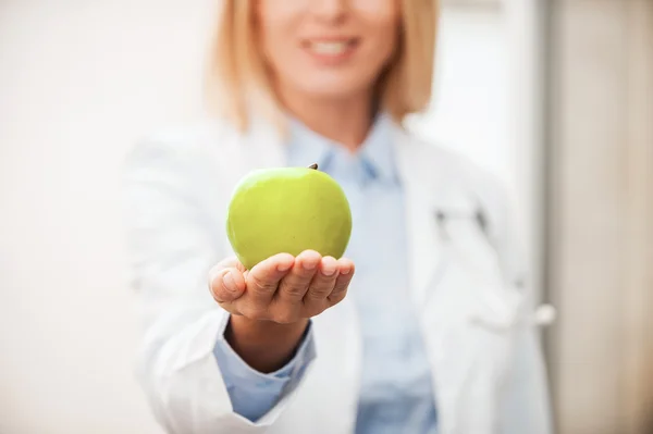 Female doctor holding green apple