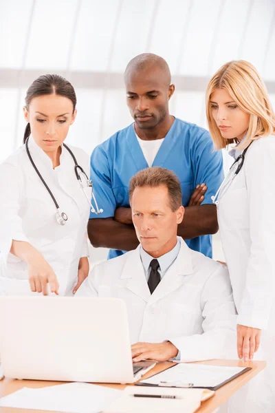 Doctors discussing and looking at laptop