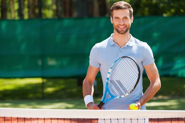 Young man holding tennis racket and ball