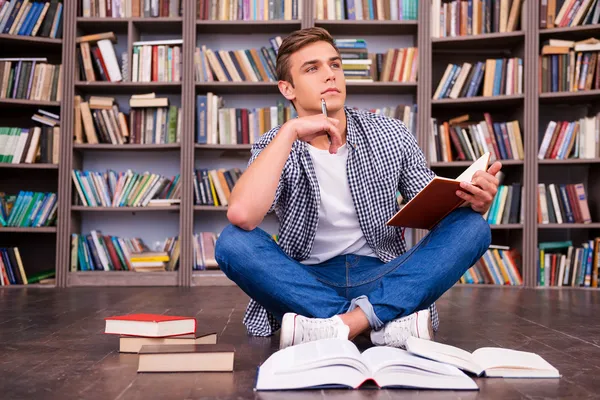 Thoughtful young man holding note pad