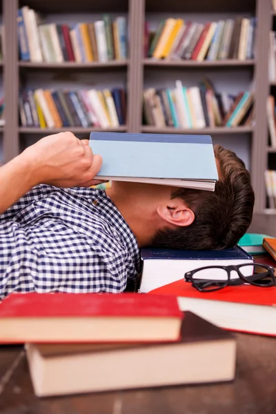 Young man covering his face with book