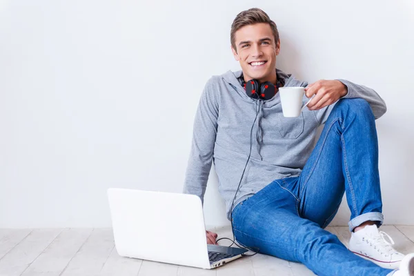 Young man headphones, coffee cup and laptop