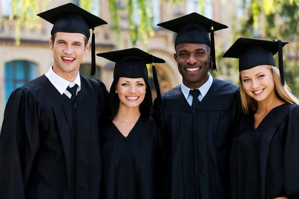 Four college graduates in graduation gowns