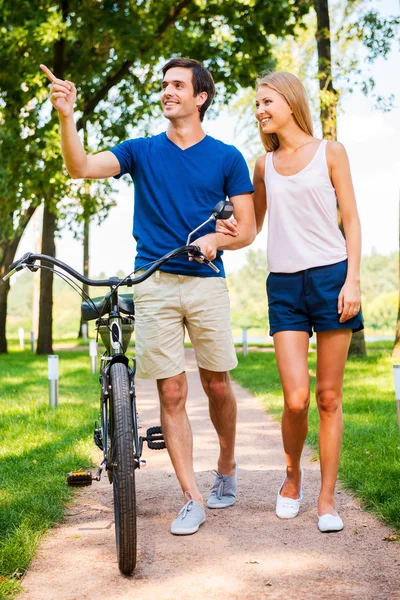 Couple walking with bicycle in park