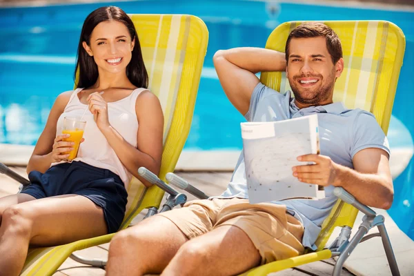 Couple relaxing at the deck chairs by the pool