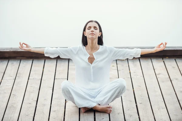 Woman in white clothing sitting in lotus position