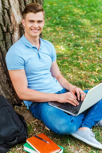 Student working on laptop on the grass