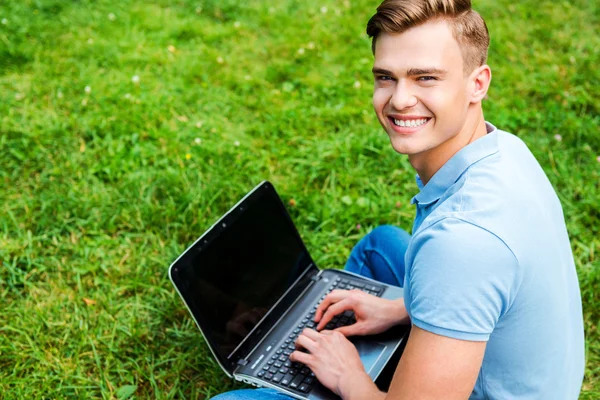 Man sitting on the grass with laptop