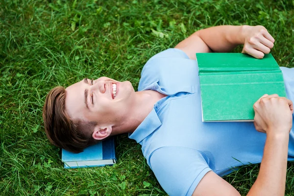 Man holding  book and lying on grass