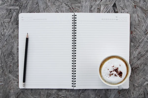 Cup of coffee and notebook paper on a wooden table