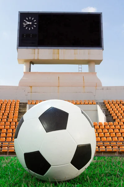 Soccer ball on the green grass with score board