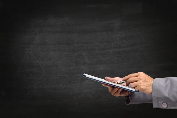 Hand writing on a tablet, with blackboard background