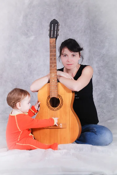Mother teaches child playing guitar