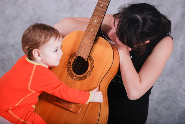 Mother teaches child playing guitar