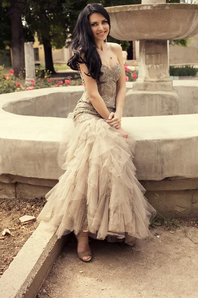 Beautiful smiling woman in luxurious dress posing at antic park
