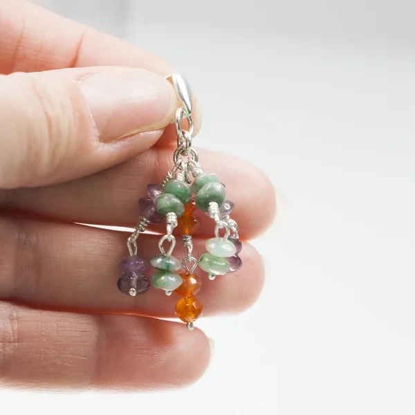 Hand holding Silver earrings with amethyst, agate and emerald gemstones
