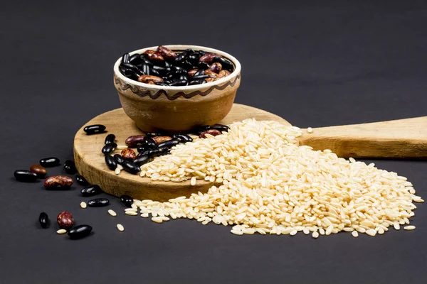 Beans in a ceramic pot, paddy rice and kitchen cutting board