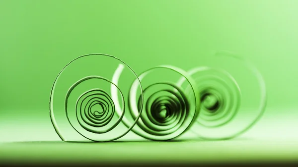 Green paper spirals on paper background