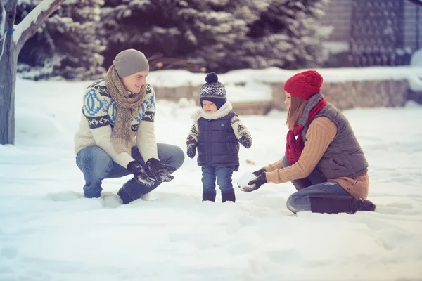 Happy young family portrait on winter surrounded by snow.