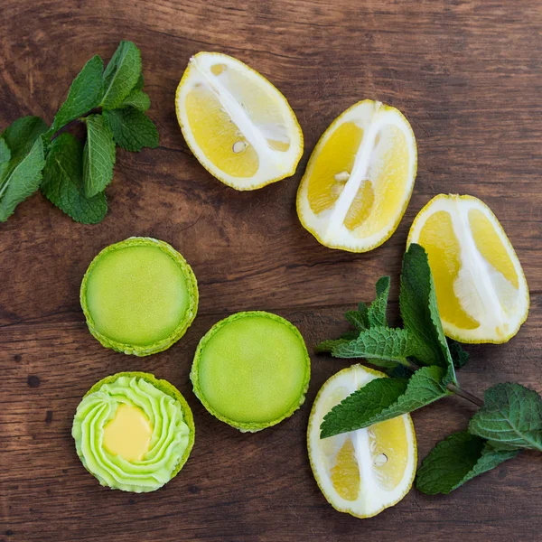 Lime green macarons with lemon and mint on wooden background