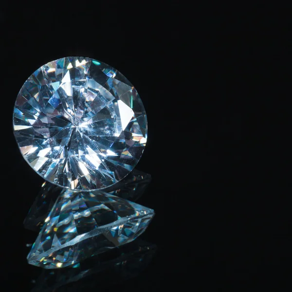 Blue diamond on black background with reflection