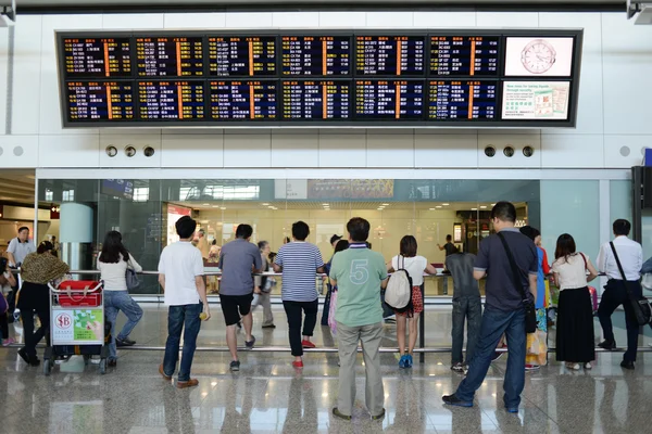 Hong Kong, China - September 14, 2013: Passengers looking at the large arrival board at Hong Kong Airport