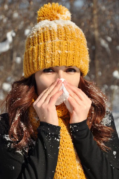Woman sneezing into tissue, winter outdoor portrait