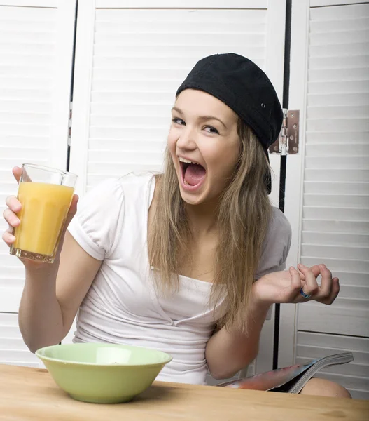 Portrait of funny teenage girl in white dress and sunglasses, having breakfast