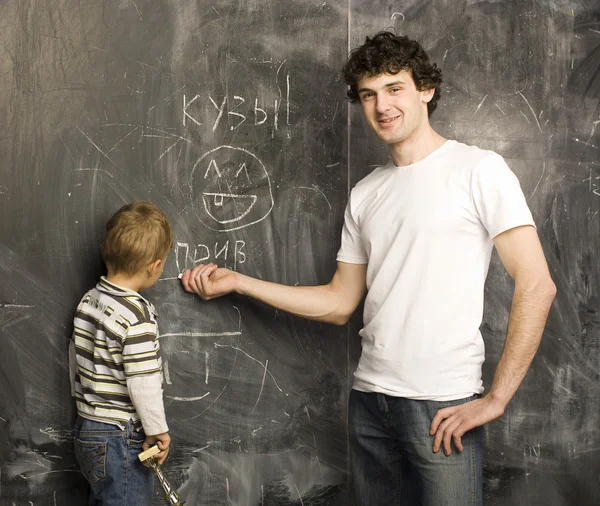 Portrait of teacher and little student, father and son near blackboard