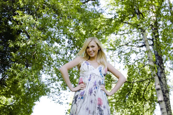 Happy blond young woman in park smiling