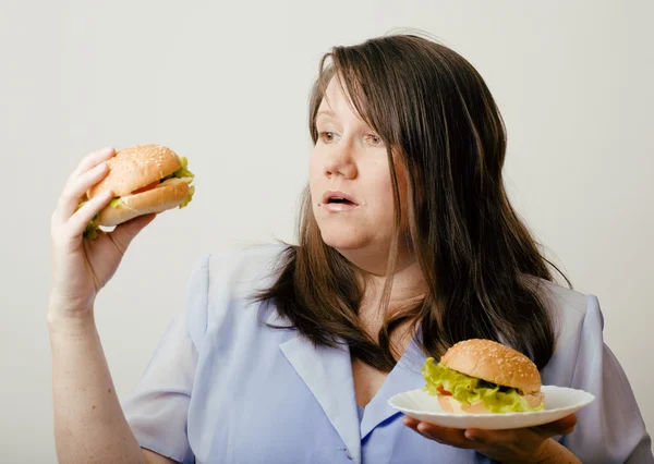 Fat white woman having choice between hamburger and salad