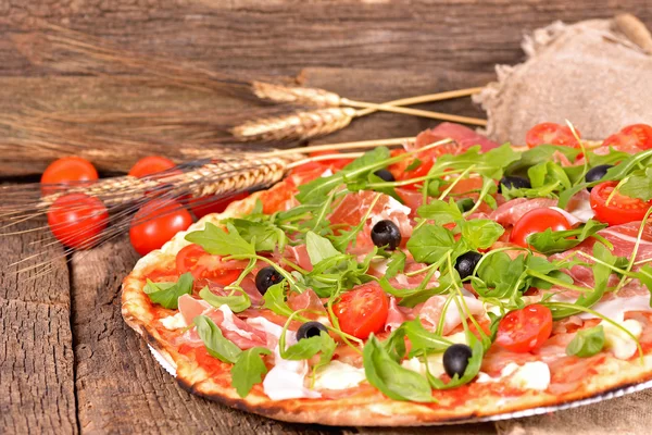 Italian pizza with ham, mozzarella and arugula