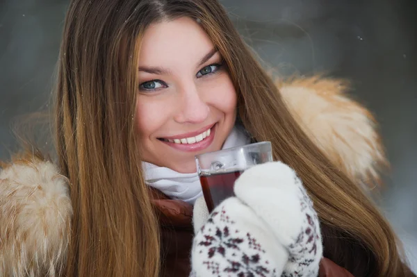 Girl drinking hot tea in the winter forest