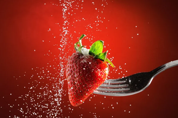 Strawberry on a fork punctured falling sugar detail
